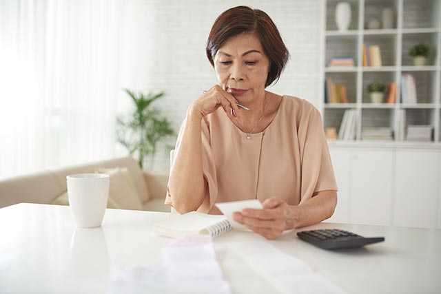 A woman calculating her finances and worrying about the burden of illness