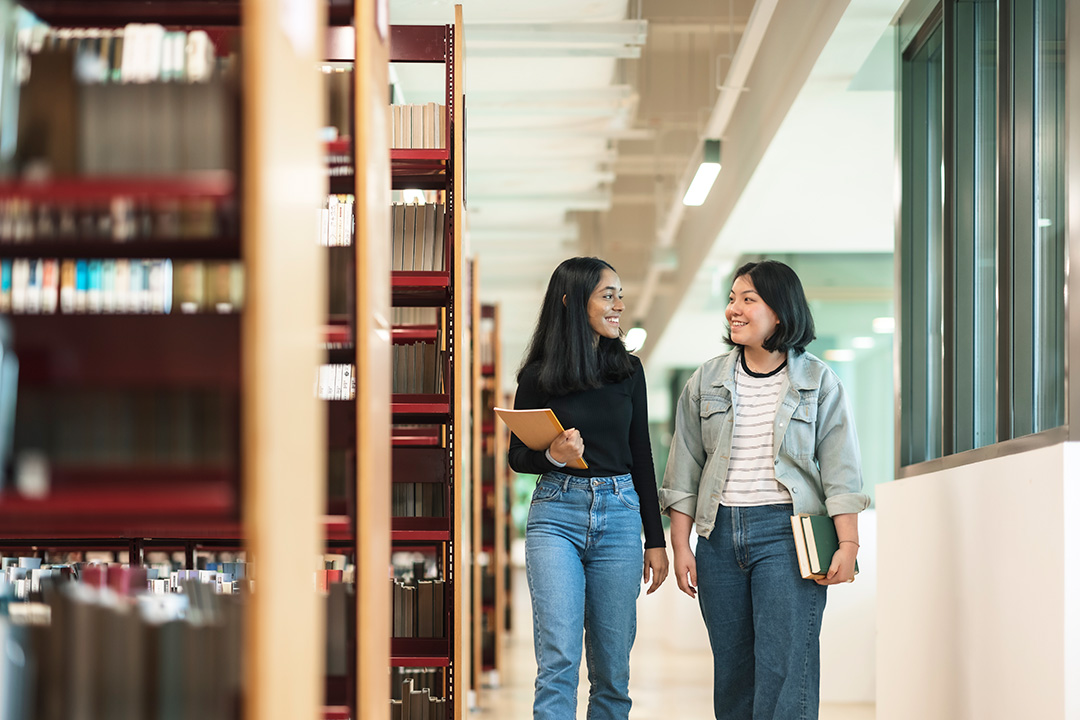students walking down the library aisle