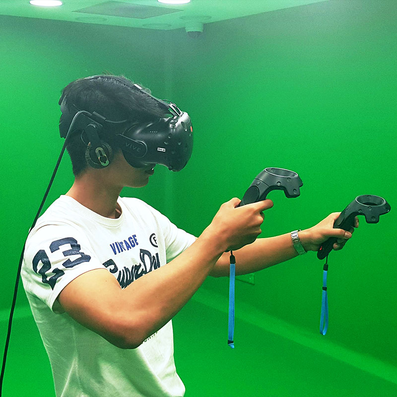 user in green room holding the HTC Vive