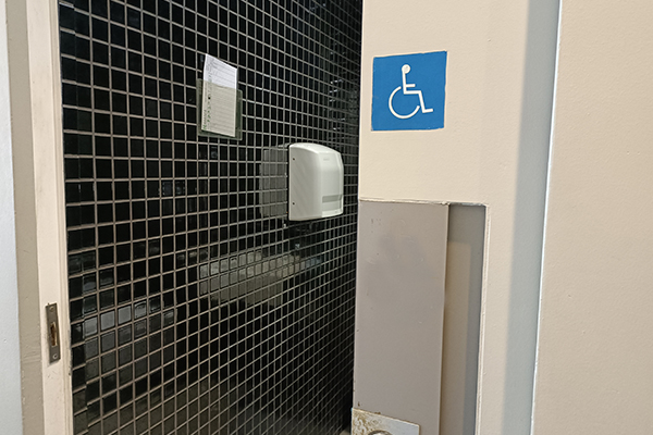 An entrance to a wheelchair accessible toilet indicated by a blue wheelchair icon sign.