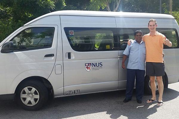A driver and student passenger posing in front of the NUS mobility van.