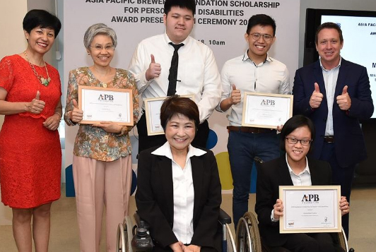 A group photo taken at an award ceremony, including person with and without disabilities. 